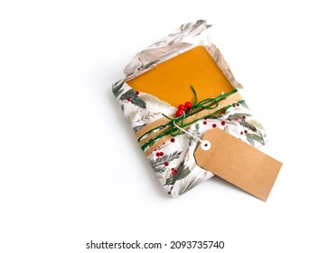 A Half Open Christmas Present Or Gift With Christmas Wrapping Paper, Twine, Ribbon, Present Topper And A Blank Gift Tag. Copyspace, Isolated On White Background. Opening Christmas Gift Concept.