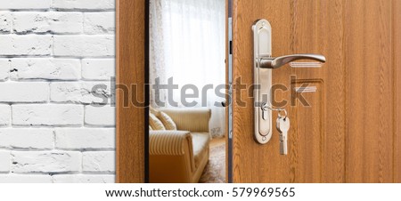 Half opened door handle closeup, entrance to a living room. Welcome, privacy concept. Door lock with keys, white brick wall, modern interior design.
