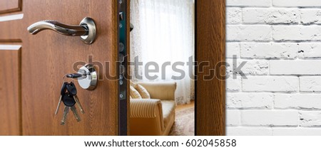 Half opened door handle closeup, entrance to a living room. Welcome, privacy concept. Door lock with keys, white brick wall, modern interior design.