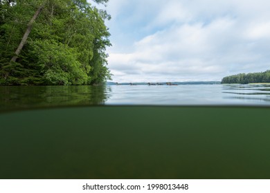 Half Over Half Under The Water Surface At Lake In Finland. Half Underwater View. Beautiful Blue Sky And White Clouds.