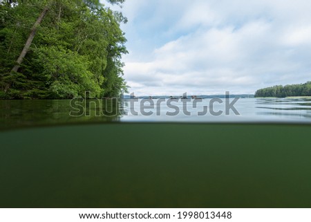 Half over half under the water surface at lake in Finland. Half underwater view. Beautiful blue sky and white clouds.
