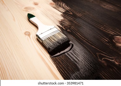 Half painted wooden surface. Black color. Varnishing natural wood with paint brush.