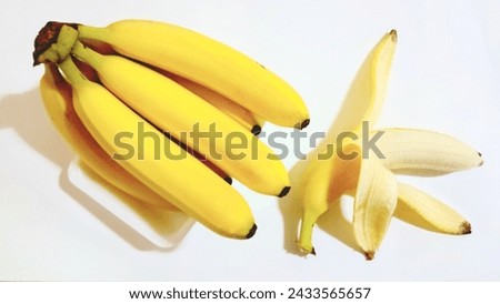 Half of a peeled banana is supported by another banana on a gray table. Fresh fruit concept.