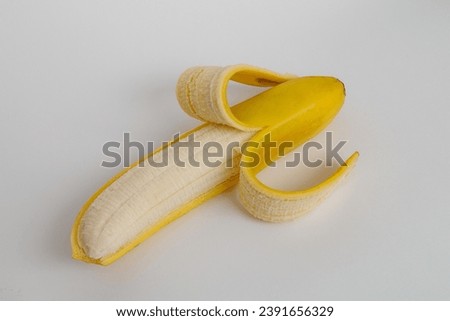 half peeled ripe banana on a white background.