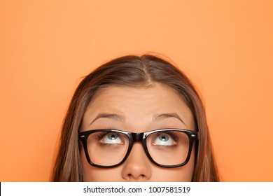 half portrait of a young girl with glasses looking up