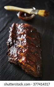 Half Rack Of Barbecued Baby Back Ribs With Sauce On Slate