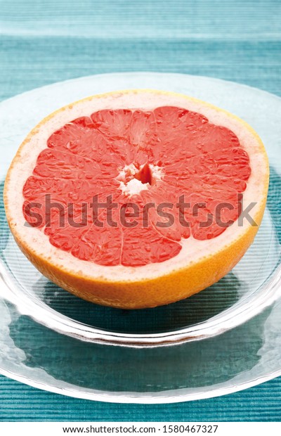 Half of\
a red grapefruit, Ruby Star, on a glass\
plate