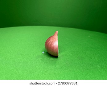 Half of a red onion cut vertically on a textured green surface half onion vegetable