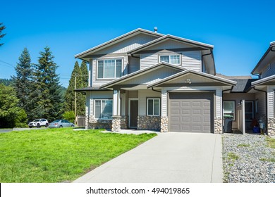 Half Of Residential Duplex Building With Concrete Drive Way And Green Lawn In Front. One Family Dwelling With Two Cars Parked On Side