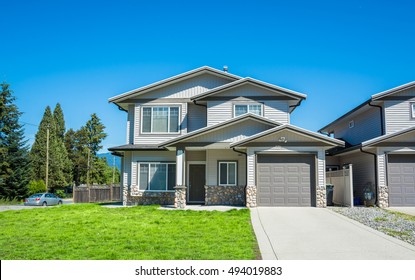 Half Of Residential Duplex Building With Concrete Drive Way And Green Lawn In Front. One Family Dwelling With Car Parked On Side