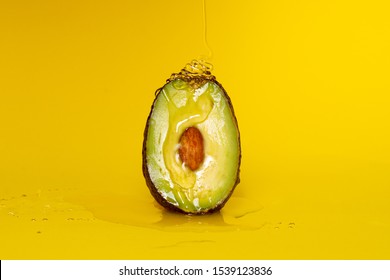 Half of ripe avocado with honey on yellow background. Clitoral or vaginal orgasm. Vagina symbol. Sex concept.