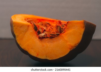 Half of a ripe orange pumpkin on a wooden table. Pumpkin seeds. Halloween. Autumn vegetable harvest.  An ingredient for cooking Thanksgiving dishes. Cooking pumpkin soup or pie