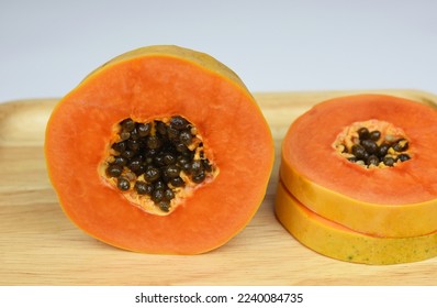 half of ripe papaya fruit with seeds on wooden board . - Shutterstock ID 2240084735