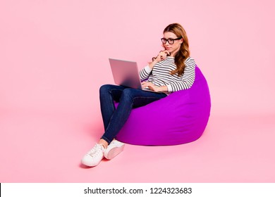 Half turn full legs body size lady with her trendy brown wave curly hair she isolated pink background sit in spectacles shoes striped casual clothes jeans denim wear look at pc gadget use internet - Powered by Shutterstock