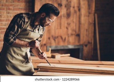 Half turned photo portrait of serious focused concentrated thoughtful handsome bearded strong masculine busy professional foreman builder using equipment wooden plank