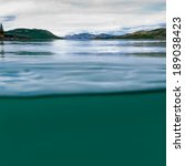 Half underwater half over, over-under split shot of huge Lake Laberge, Yukon Territory, Canada, clear blue freshwater and distant shore boreal forest taiga landscape