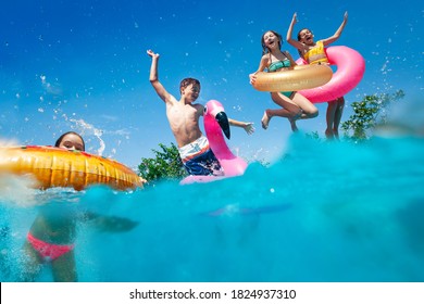 Половина подводного сплит-изображения многих маленьких детей погружаются в бассейн бросают надувные игрушки, поднимая руки, весело