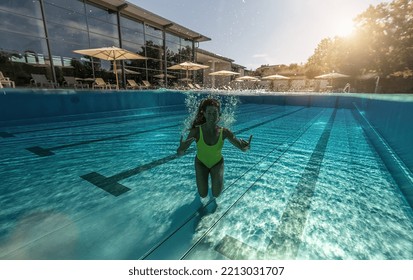 Half Underwater Split Image Of A Woman Swimming In Swimming Pool At A Hotel Or Spa Resort