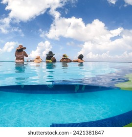 Half underwater split image of young women having fun in hotel pool in Caribbean sea. Concept of vacation and bachelorette pool party