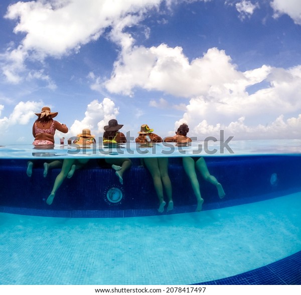 Half underwater split image of young women having\
fun in hotel pool in Caribbean sea. Concept of vacation and\
bachelorette pool party