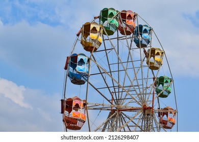 Half View Of The Empty Carnival Ferris Wheel Against The Blue Sky.