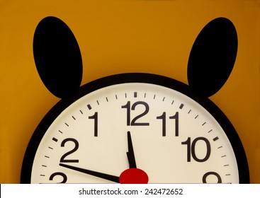 Half of a wall clock with red nose, black ears and the order of the numbers inverted