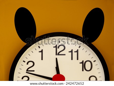 Half of a wall clock with red nose, black ears and the order of the numbers inverted