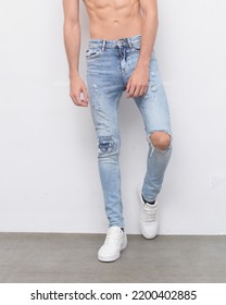 Half Young Man In Torn Jeans With Shoes In Studio Background