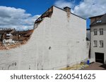 The half-destroyed high brick wall of the house is slated for demolition. Against the background of the blue sky and another house