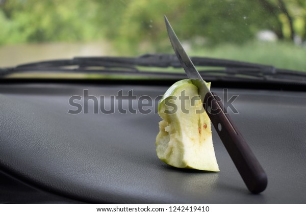 half-eaten apple with a knife lies in the car\
near the windshield