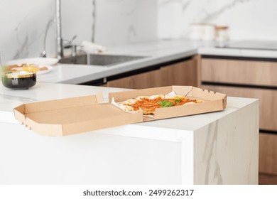 Half-eaten pizza in an open box sits on sleek, modern kitchen counter, highlighting casual and relaxed home dining moment. - Powered by Shutterstock