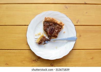 Half-eaten slice of pecan pie on a china plate with a dessert fork