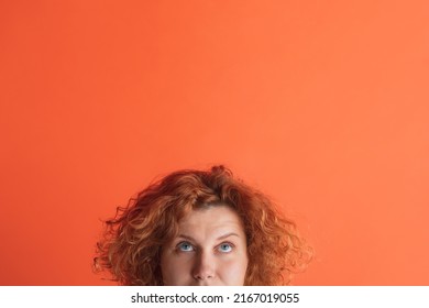 Half-faced portrait of red-haired woman posing, isolated over red studio background. Looking upwards. Thoughtful. Concept of facial expression, emotions, feelings, ads - Powered by Shutterstock