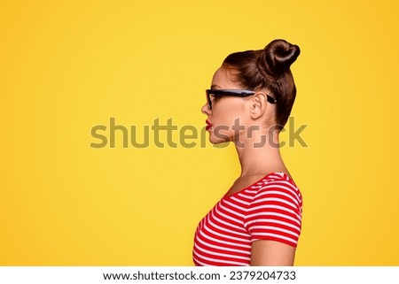 Half-faced side profile view portrait of serious and confident young woman in striped shirt and spectacles isolated on red vivid background with copy space