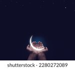 A Half-illuminated moon in hand. Ramadan and Eid Greetings concept. Muslim Holidays and Eid-Ul-Adha festival celebration.