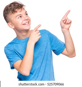 Half-length Emotional Portrait Of Caucasian Teen Boy Wearing Blue T-shirt. Funny Teenager Pointing And Looking Upwards While Smiling, Isolated On White Background. Handsome Happy Child Pointing Up