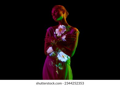 Half-length image of young relaxing woman posing in neon light isolated on dark mode background. Flower reflection. Copy space for ad. Concept of emotions, facial expression, youth, aspiration.