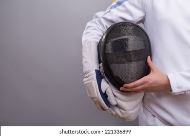 Half-length portrait of the girl wearing white fencing costume holding the fencing mask. Isolated on grey background - Powered by Shutterstock