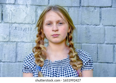 Half-Length Portrait Of a teenage girl with two pigtails against a light brick wall. - Powered by Shutterstock