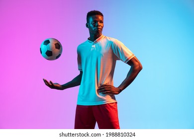 Half-length portrait of young African man, professional football player standing isolated on gradient blue pink background in neon light. Concept of action, team game, energy, sport. Copy space for ad - Powered by Shutterstock