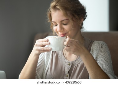 Half-length portrait of young beautiful female sitting at coffee shop with cup of tea or cappuccino. Woman enjoying hot drink in the morning. Attractive model sipping coffee with closed eyes - Powered by Shutterstock