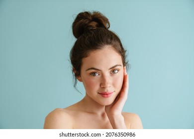 Half-naked brunette woman posing and looking at camera isolated over blue background