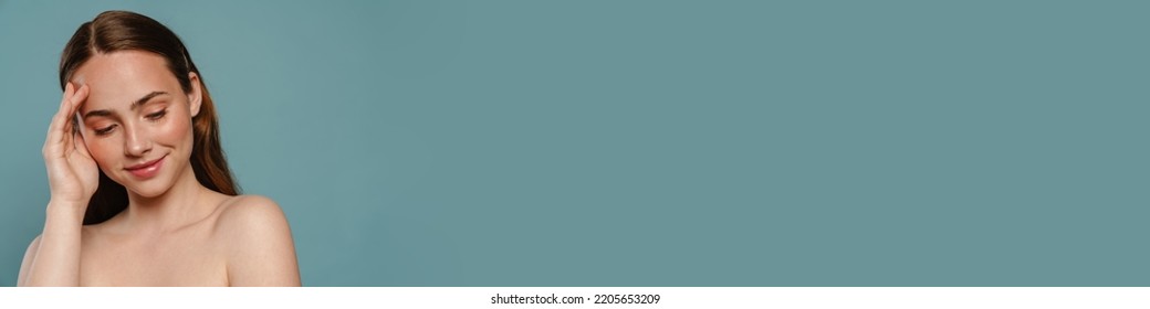 Half-naked Ginger Woman Smiling And Looking Downward Isolated Over Blue Background