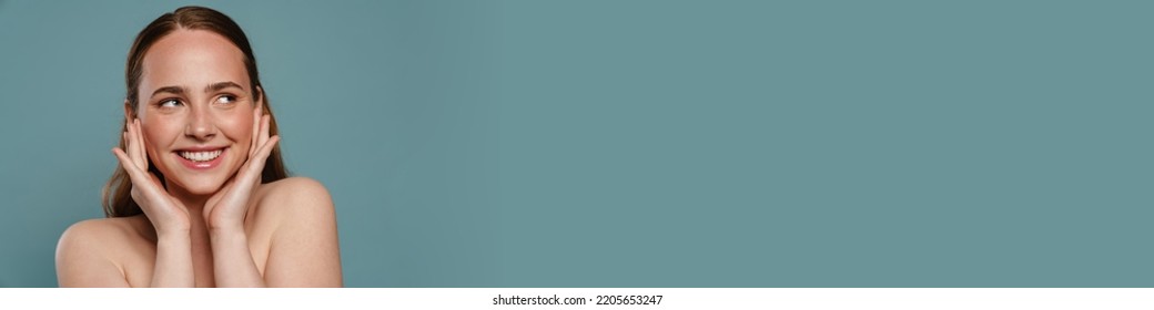 Half-naked Ginger Woman Smiling And Looking Aside Isolated Over Blue Background