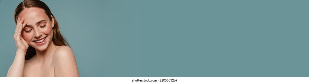 Half-naked Ginger Woman Smiling And Looking Downward Isolated Over Blue Background