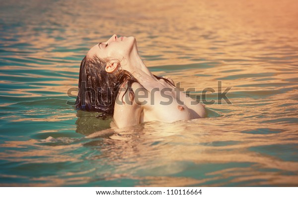 Silhouette Of A Woman Sitting On A Beach At Sunset Stock 