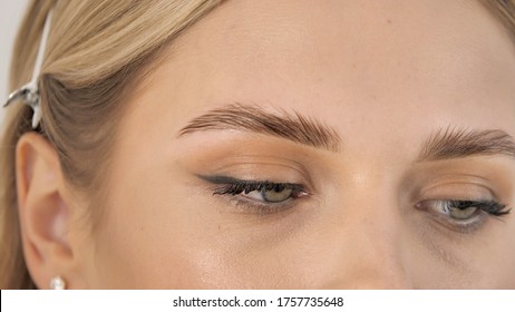 Half-open female beautiful eyes look aside close-up.  Attractive female face of a blonde well-groomed woman or lady. Successful business woman. Adult blonde girl with makeup