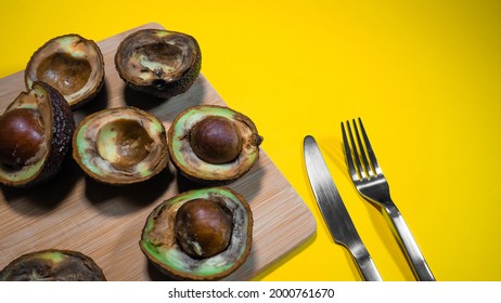 Halfs Rotten Avocado. Unhelthy Food Concept. Close Up Bad Avocado On Yellow Background. Ugly Fruits.