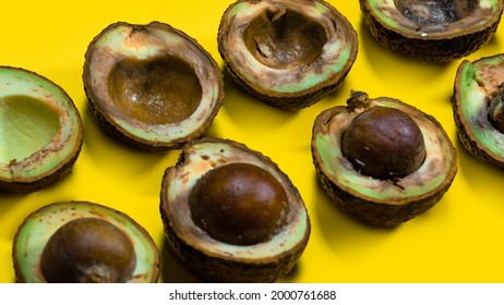 Halfs Rotten Avocados On Yellow Table. Unhelthy Food Concept. Close Up Bad Avocado On Yellow Background.