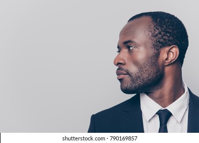Half-turned side profile close up view portrait of handsome virile masculine attractive confident smart intelligent clever african man looking aside weairng smartsuit isolated on gray background
